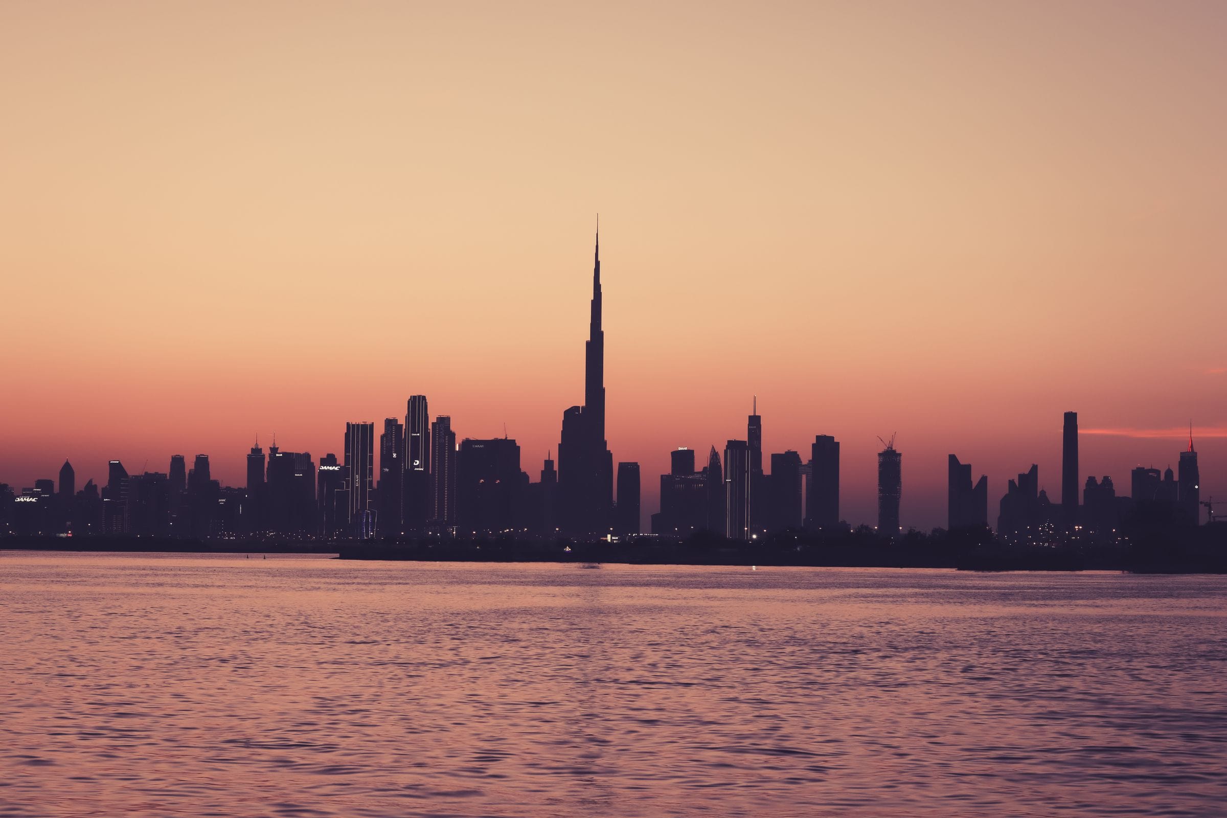 The Burj Khalifa skyline in silhouette at dusk, seen across the water