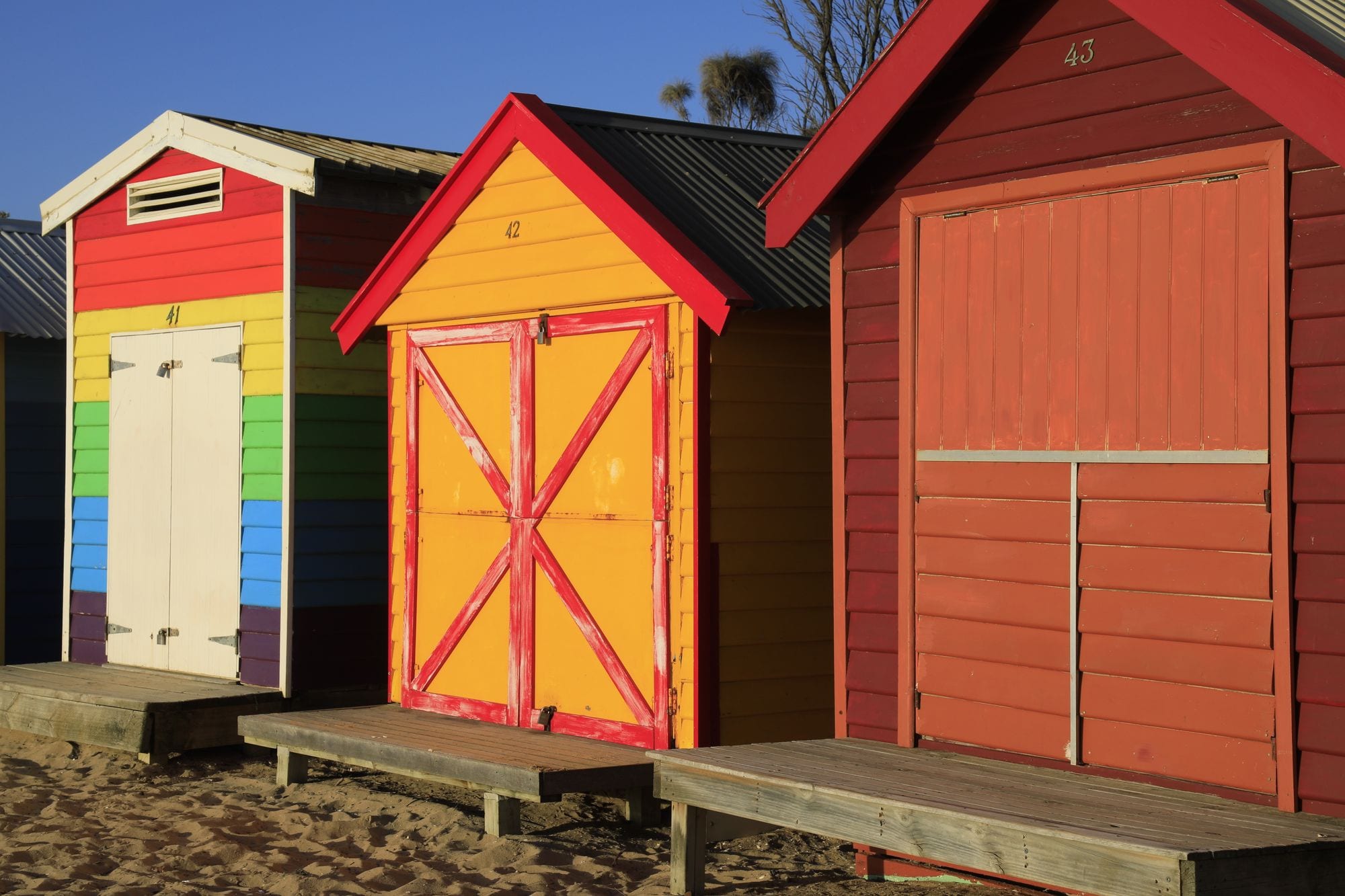 Brightly painted Brighton bathing boxes glowing in golden-hour light, Melbourne