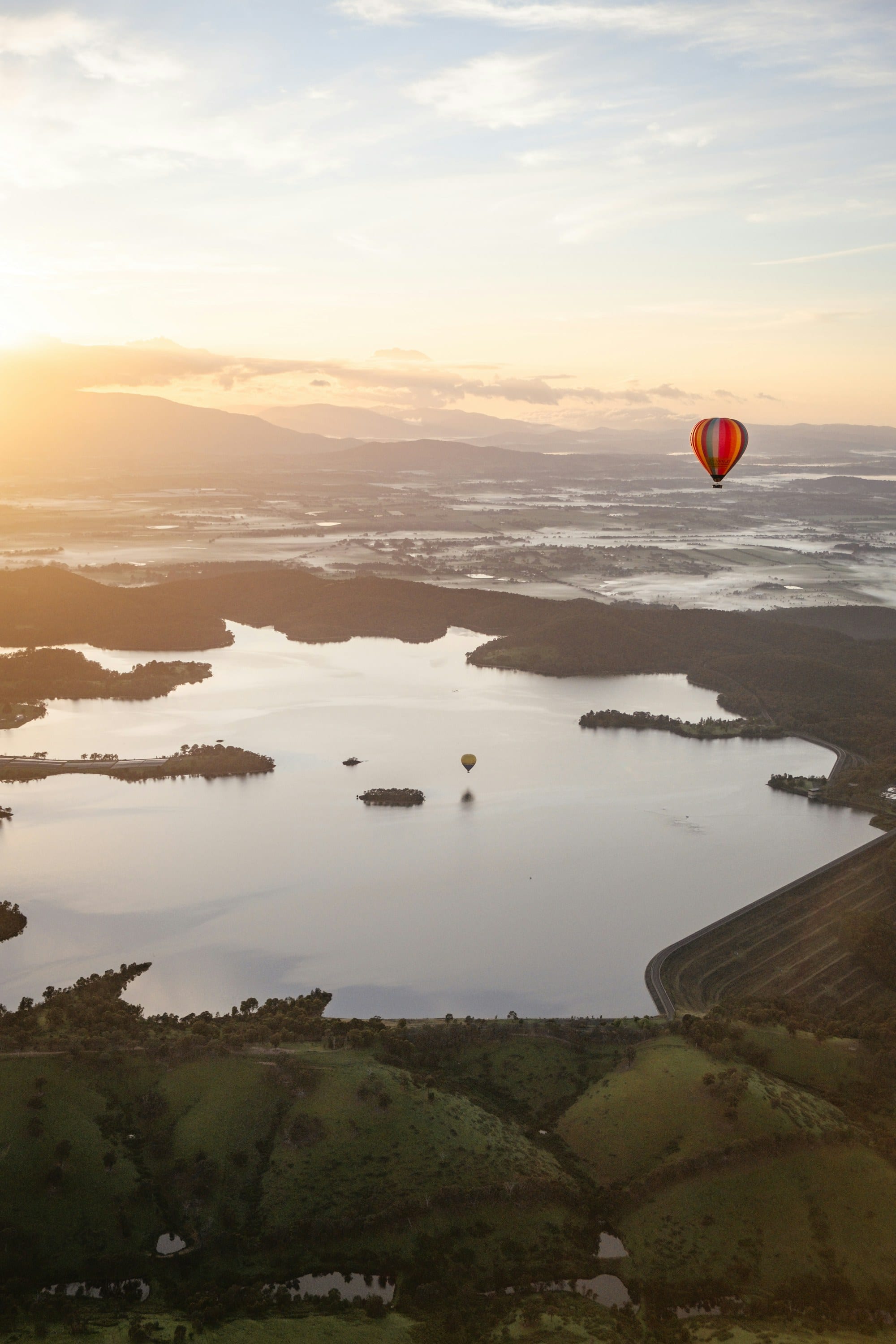 Hot air balloons drifting over misty water at sunrise in the Yarra Valley near Melbourne
