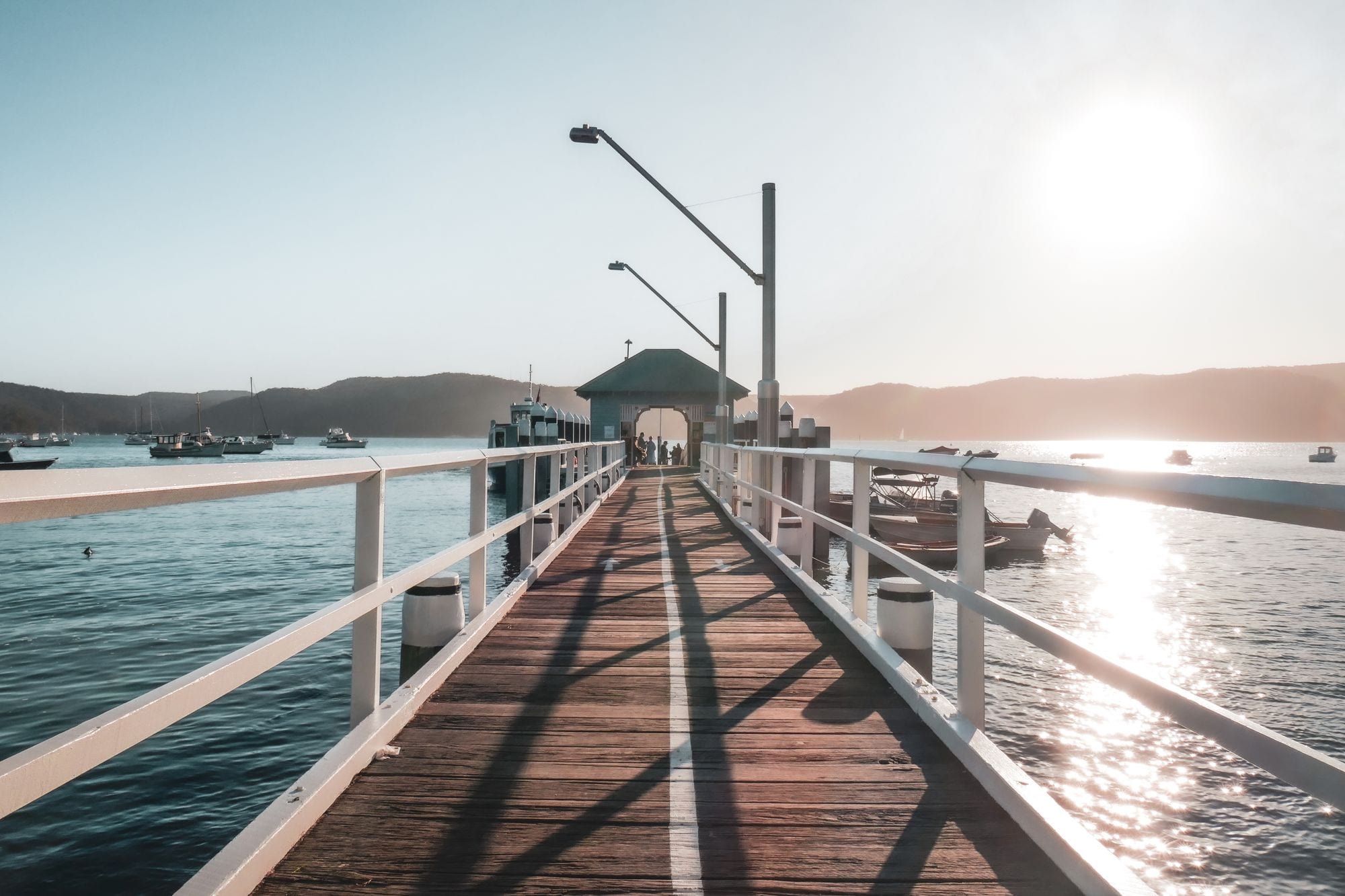 Late sun washes over Palm Beach wharf and moored boats on Pittwater, Sydney