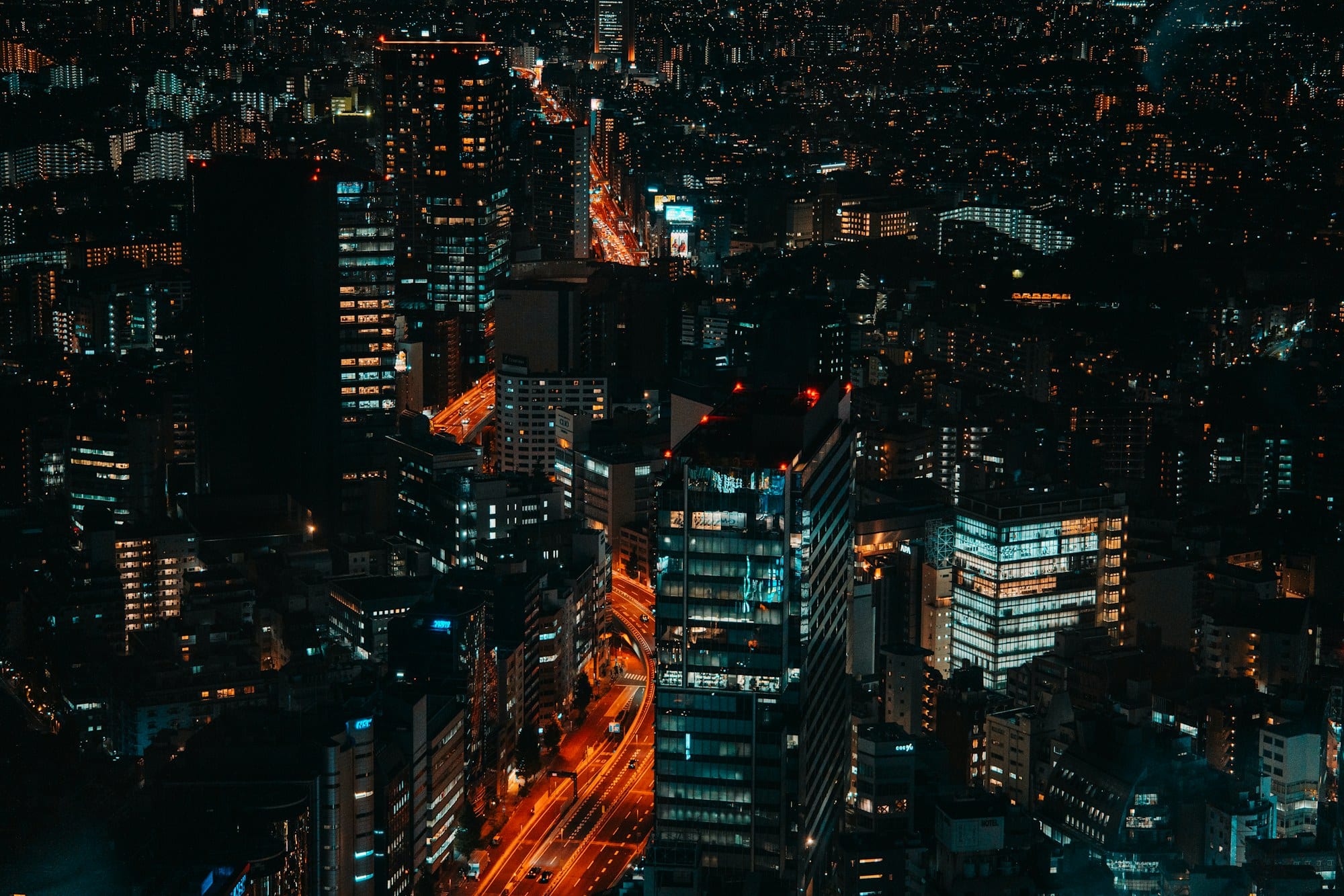 Tokyo's amber-lit streets and glass towers seen from high above after dark