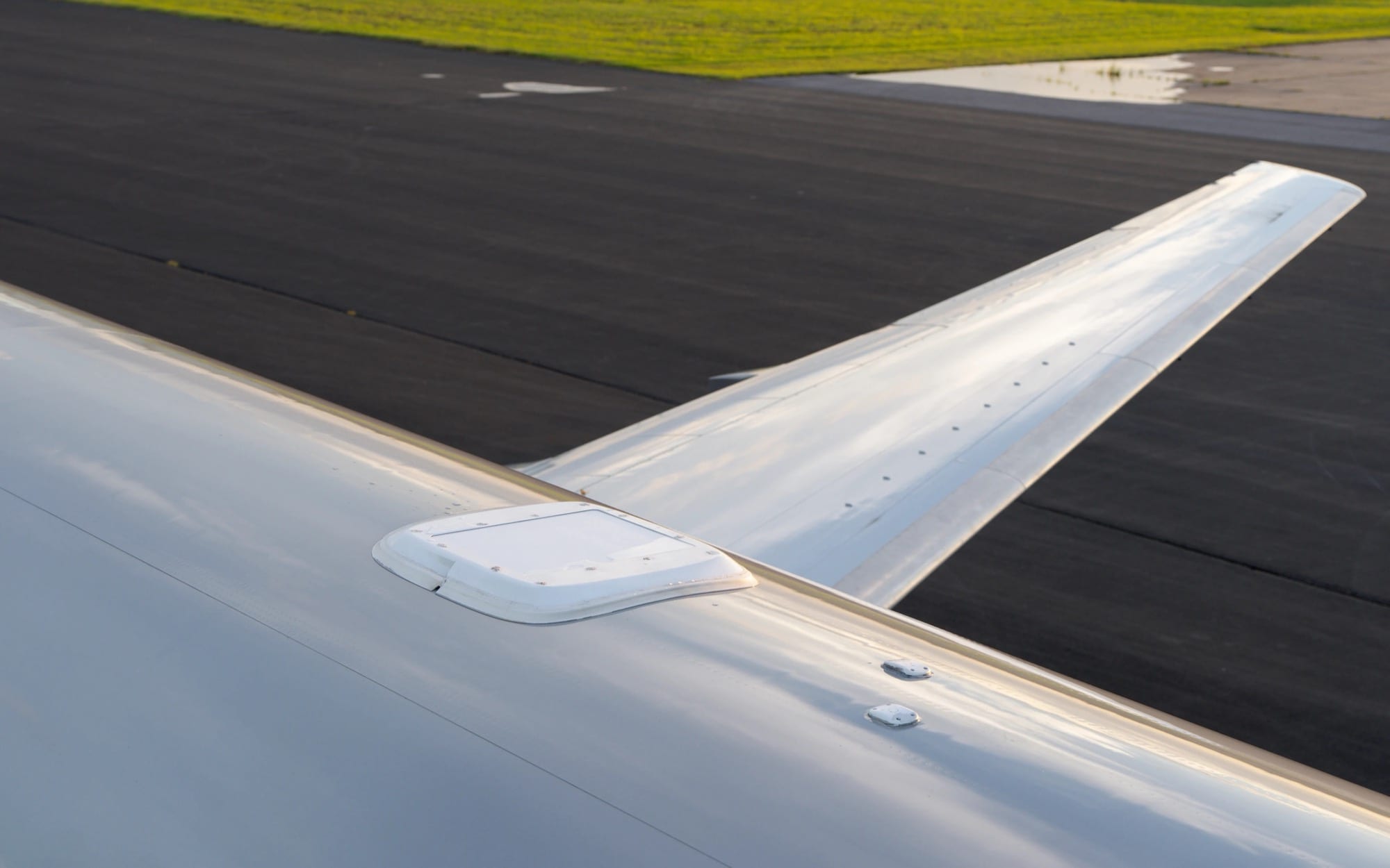 A low-profile satellite antenna fairing sitting nearly flush with an aircraft's fuselage crown, tailplane beyond
