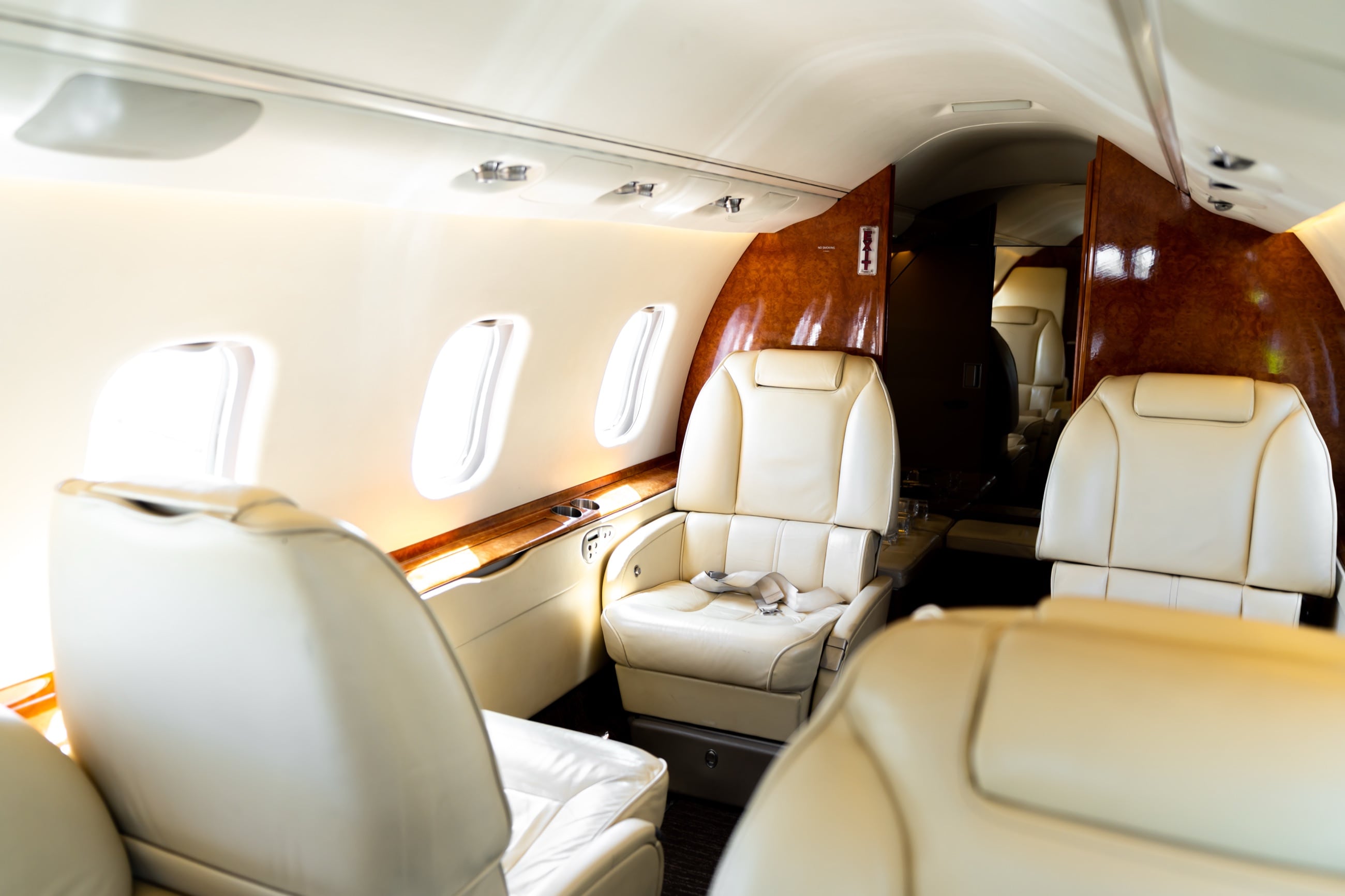 The Learjet 60 cabin — cream leather club seating and polished wood, sunlit