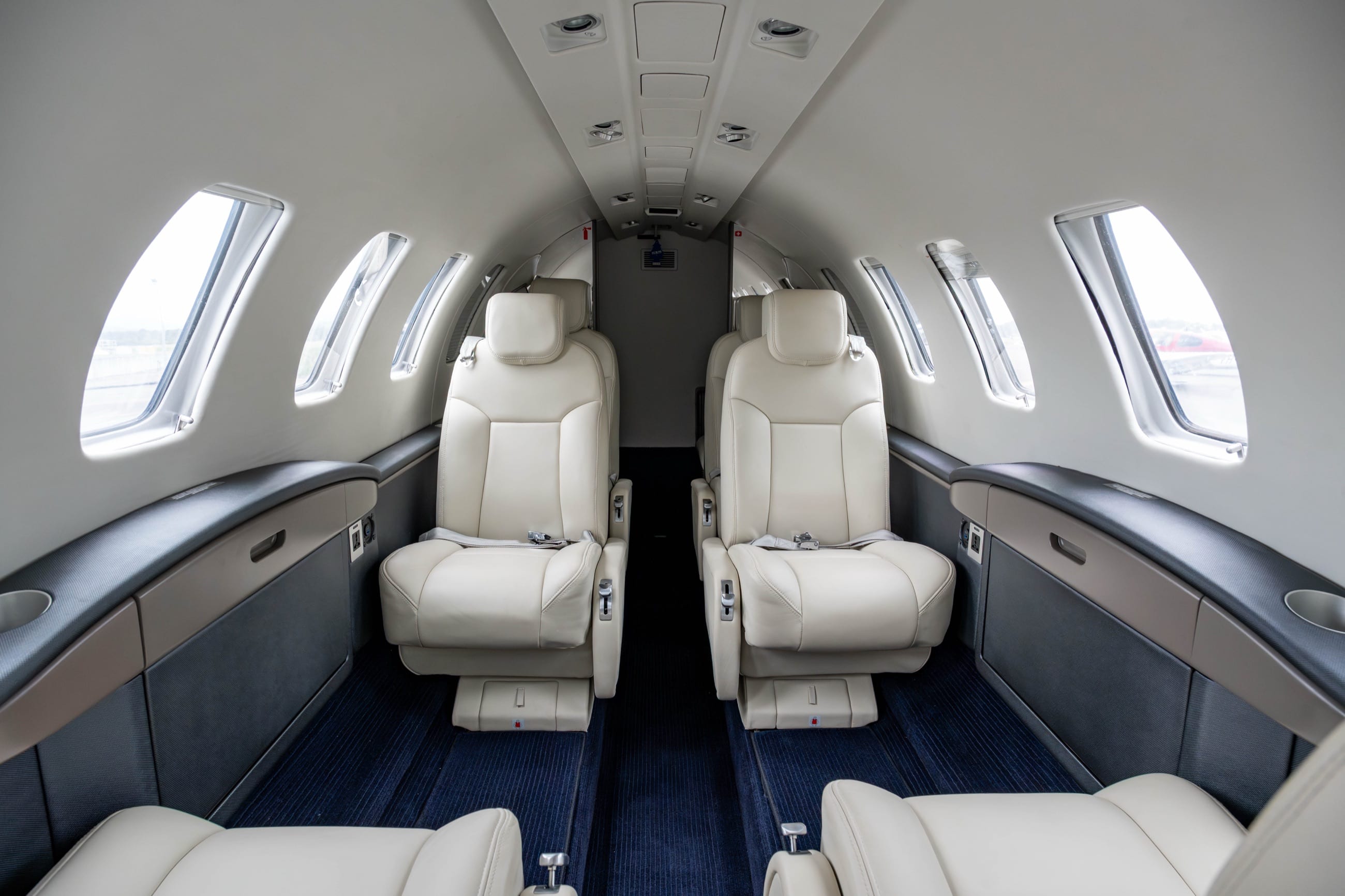 The CJ2+ cabin — executive club seating in soft leather, sunlit through the starboard windows