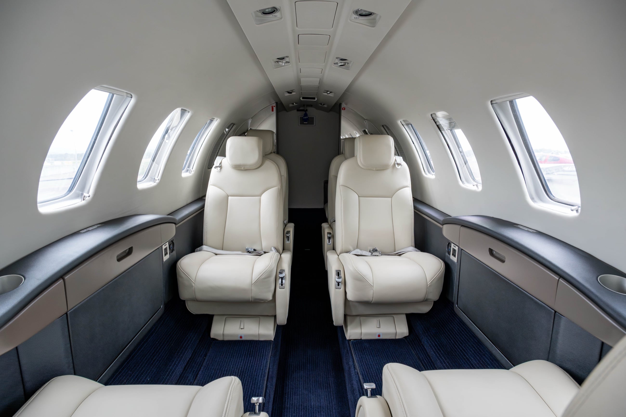 The CJ2+ cabin — executive club seating in soft leather, sunlit through the starboard windows