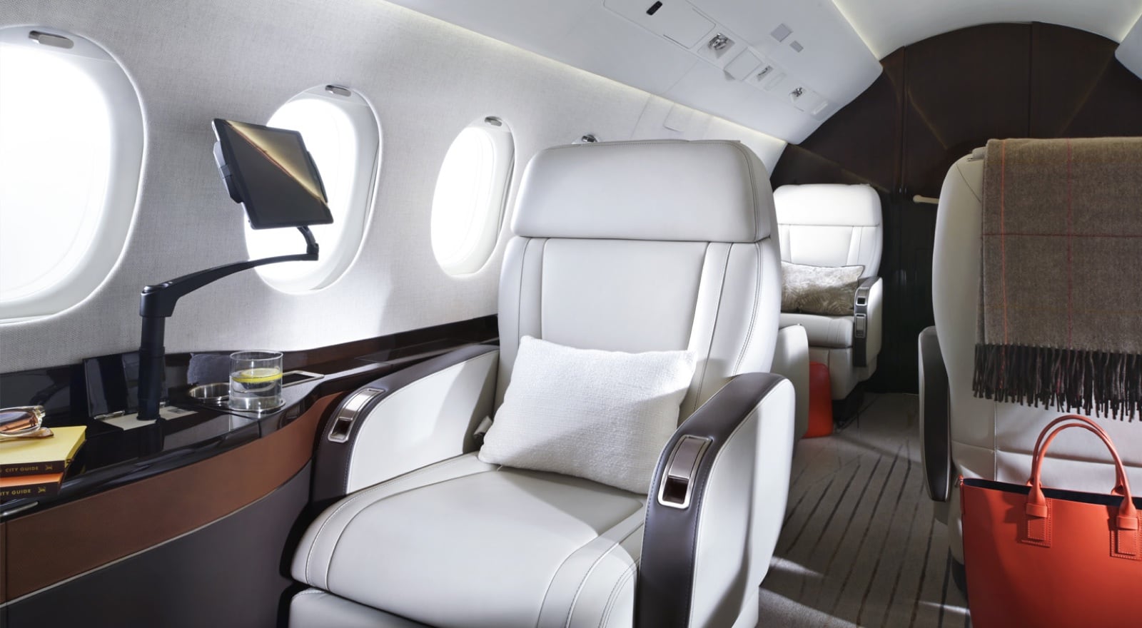 The Falcon 2000LXS cabin — wide-body club seating in pale leather