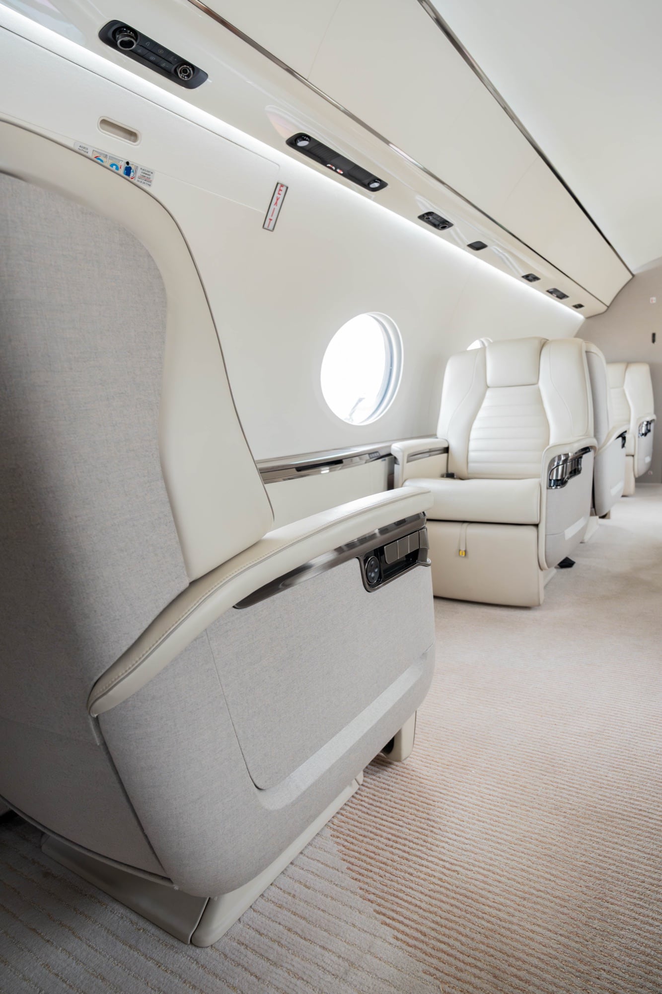 A G700 living area — facing seats in cream leather beside panoramic oval windows