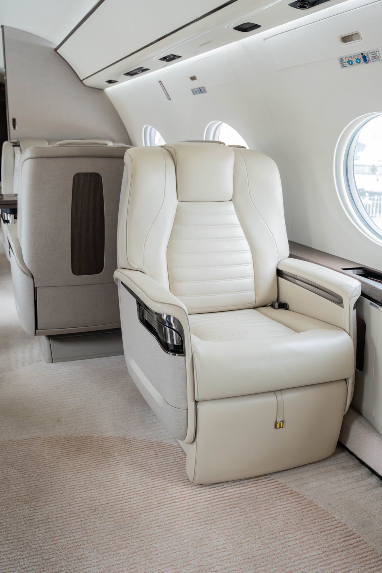 The cabin of a Gulfstream G700 in cream leather, lit by oval windows