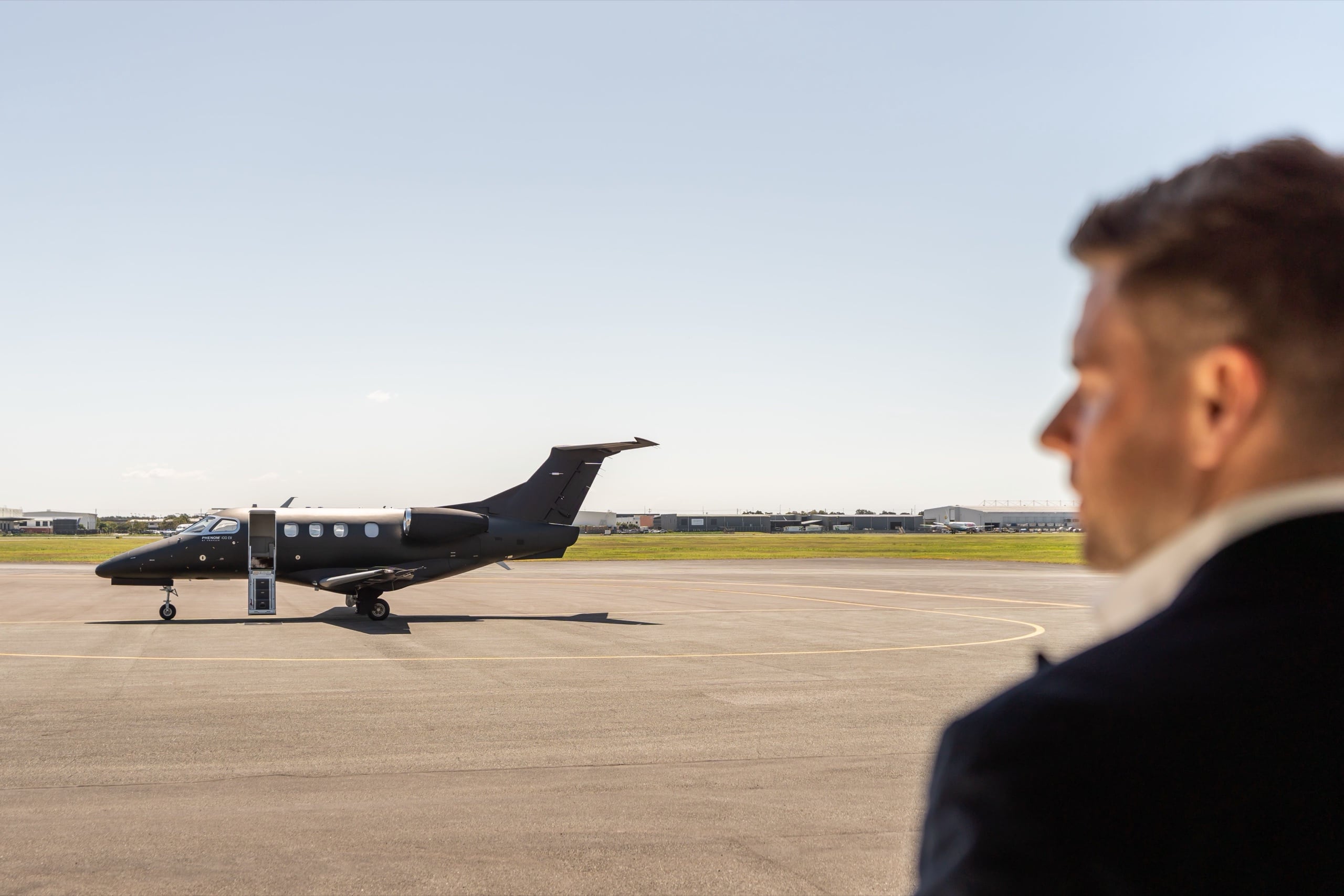 A buyer surveys a black Phenom 100EV waiting on the apron