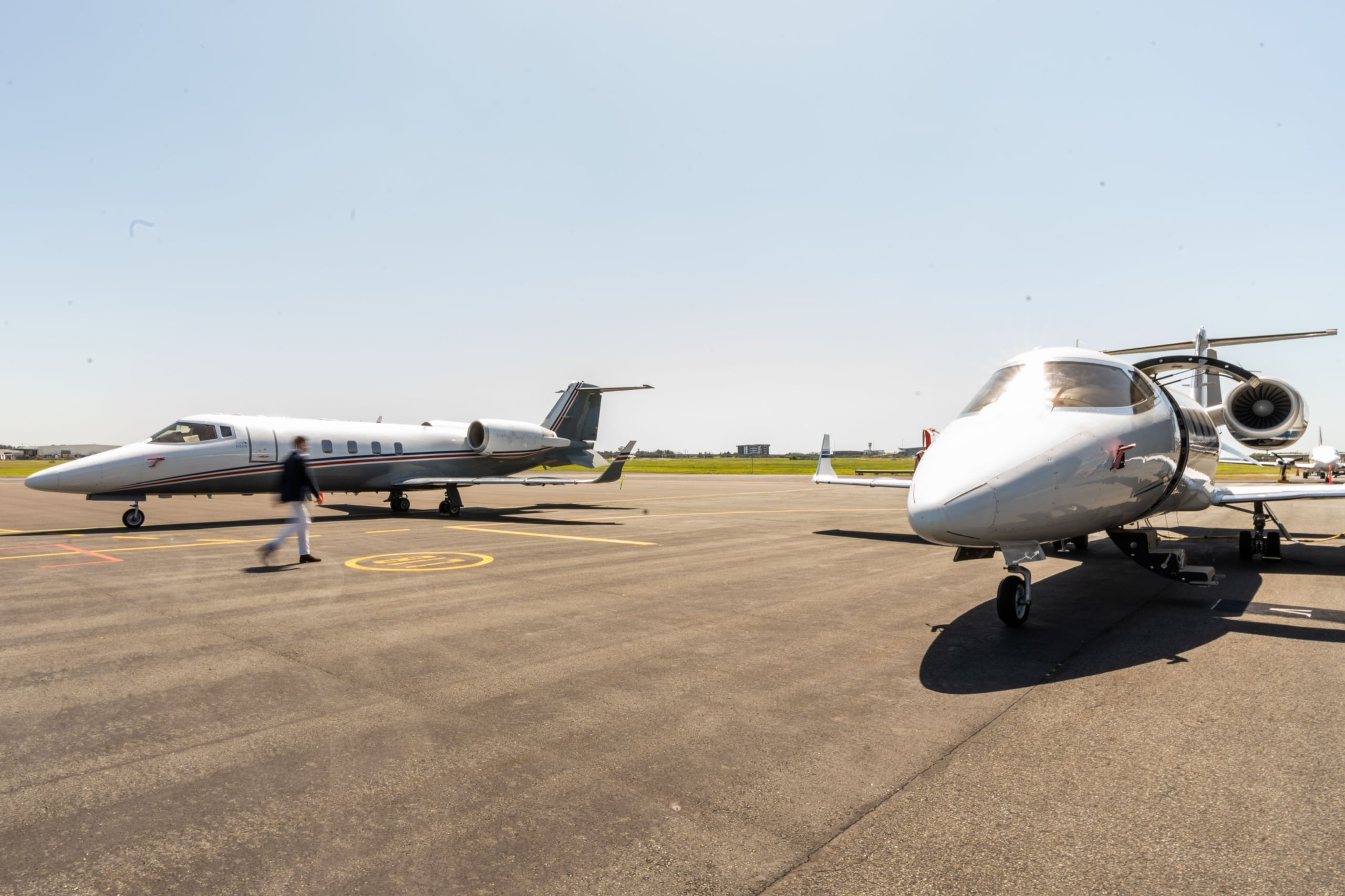 Two Learjets positioned on a sunlit apron between flights